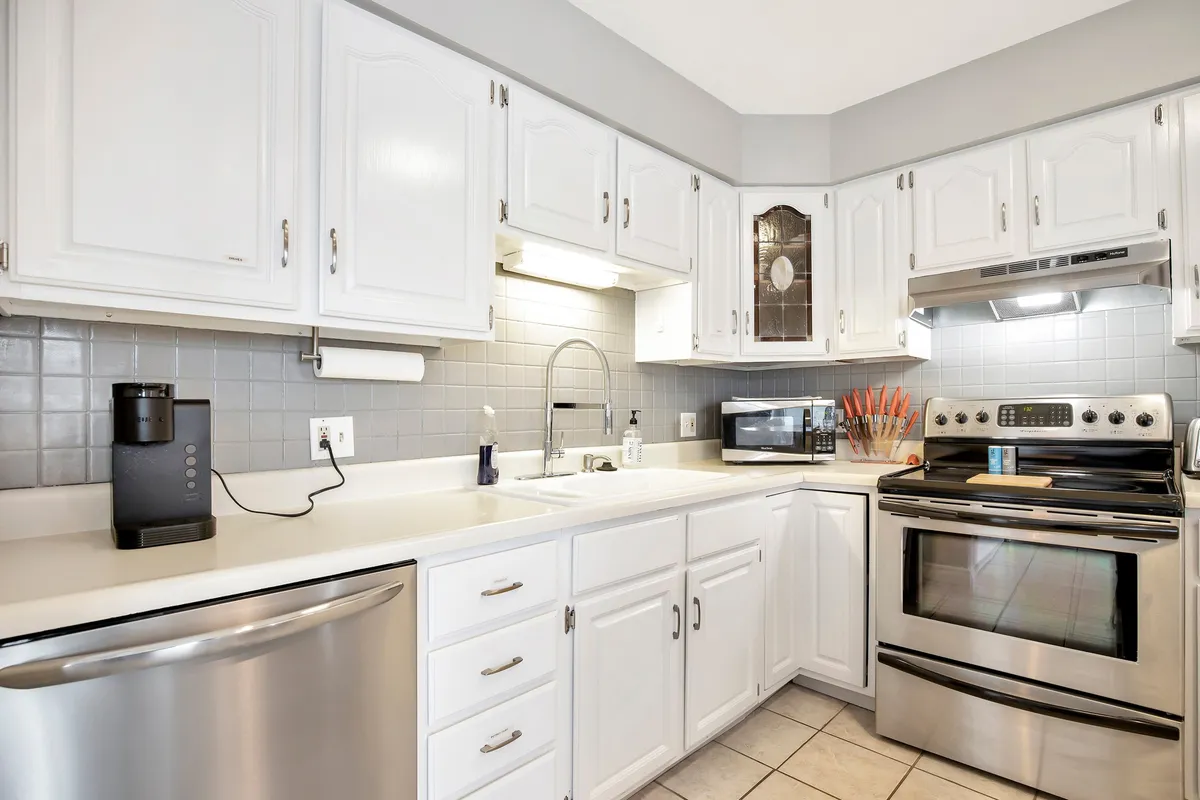 This image highlights the kitchen’s modern stainless steel appliances, white cabinetry, ample counter space, and sink, making it easy to visualize a fully equipped and welcoming cooking environment.