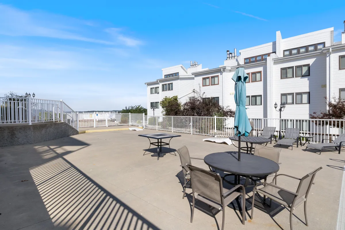 A cozy outdoor seating area with an umbrella set amidst lush greenery on a private patio, offering an inviting spot for relaxing or sharing a drink. The horizon glows with the warm colors of sunset, creating a romantic and tranquil atmosphere suited for couples.